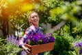 Young woman moving purple petunias in plant pot smiling