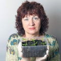 A female gardener shows a pot with sprouts after a pick