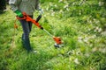 Female gardener using electric string trimmer to trim grass in garden Royalty Free Stock Photo