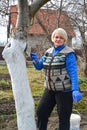 A female gardener whitewashes the trunk of a fruit tree. Spring garden work Royalty Free Stock Photo