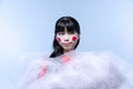 Close-up portrait of young amazing Japanese girl with bright stage make-up on white studio background.