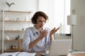 Female general practitioner wears headset video conferencing on laptop