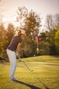 Female golf player pitching towards flag. Royalty Free Stock Photo