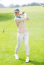 Female golfer taking a shot and smiling at camera Royalty Free Stock Photo