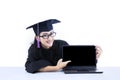 Female graduate pointing at empty laptop screen