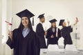 Female graduate shows the camera a diploma in her hands while standing in the classroom. Royalty Free Stock Photo