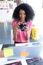 Female graphic designer reviewing photos on digital camera at desk Royalty Free Stock Photo