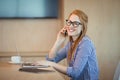 Female graphic designer talking on mobile phone while working in office Royalty Free Stock Photo