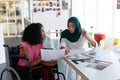 Female graphic designers discussing over photographs at desk