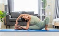 Female in green top and leggings stretching in Parivrtta Janusirsasana exercise or Revolved Head to Knee Pose on blue mat in Royalty Free Stock Photo