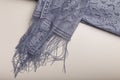 Female grey lace shawl with fringe and flowers ornaments on white table background. Clothing and accessories.
