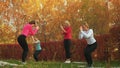 Female group practicing yoga exercise in autumn park. Relaxer woman training yoga asana on outdoor workout. Women doing