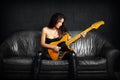 Female guitarist sitting on a leather couch Royalty Free Stock Photo