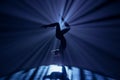 Female gymnast on dark background of studio with backlight. Acrobatic girl performing handstand. Modern choreography and Royalty Free Stock Photo