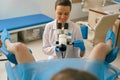 Female gynecologist examining patient on chair with gynecological equipment in woman consultation