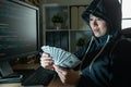Female hacker looking at money with grimace.