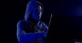 Female hacker sitting in the dark with his laptop and tries to crack the code software. Colored neon lights.