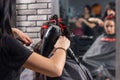 Female hair stylist with tattooed hands brushing and drying using hand held blow dryer on hair Royalty Free Stock Photo