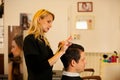 Female hairdresser cutting hair of smiling man client at beauty Royalty Free Stock Photo