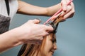 Hairdresser hands trimming client`s hair over blue background