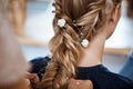 Female hairdresser making hairstyle to blonde girl in beauty salon.