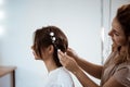 Female hairdresser making hairstyle to brunette girl in beauty salon. Royalty Free Stock Photo