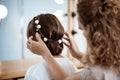 Female hairdresser making hairstyle to brunette girl in beauty salon. Royalty Free Stock Photo