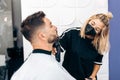 Female hairdresser with mask shaving a man using an electric machine Royalty Free Stock Photo