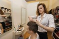 Female hairstylist cutting male customer's hair in shop