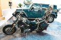 Female Halloween decorative skeleton riding on back of chopper motorcycle parked in front of store with SUV behind it