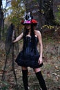 Female Halloween look. A woman in a black dress with a corset and a top-hat decorated with skeleton figures is drinking