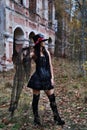 Female Halloween look. A woman in a black dress with a corset, a top hat decorated with skeleton figures poses for the