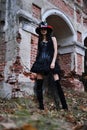 Female Halloween look. A woman in a black dress with a corset, a top hat decorated with skeleton figures poses for the