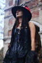 Female Halloween look. A woman in a black dress with a corset, a top hat decorated with skeleton figures poses for the
