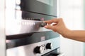 Female hand adjusting temperature on electric oven while cooking in kitchen Royalty Free Stock Photo