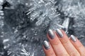 Female Hand With Beautiful Holiday Manicure - Silver Glittered Nails On Christmas Tinsel Background. Selective Focus