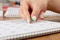 A female hand with a beautiful manicure holds a green pushpin to mark the date on the calendar Royalty Free Stock Photo