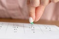 A female hand with a beautiful manicure holds a green pushpin to mark the date on the calendar Royalty Free Stock Photo