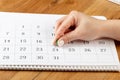 A female hand with a beautiful manicure holds a green pushpin to mark the 24 day date on the calendar Royalty Free Stock Photo