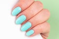 Female hand with beautiful manicure - mint blue nails with white smartphone on green background