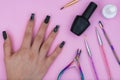 Female hand with black painted fingernails surrounded by basic elements for a manicure