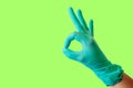 Female hand in blue latex glove makes a gesture resembling a dog with open mouth isolate malachite background. Medical health