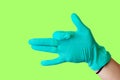 Female hand in blue latex glove makes a gesture resembling a dog with open mouth isolate malachite background. Medical health