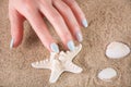Seaside Serenity: Young Girl\'s Hand with Blue Manicure and Touching Sea Starfish