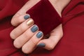 Female hand with blue nail design holding red gift box Royalty Free Stock Photo