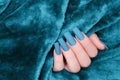 Female hand with blue nail design. Mate blue nail polish manicure. Female model hand on blue fluffy fabric