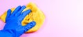 Female hand in blue rubber glove holding yellow rag on pink wall background with copy space Royalty Free Stock Photo