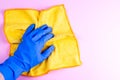 Female hand in blue rubber glove holding yellow rag on pink wall background with copy space Royalty Free Stock Photo