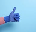 Female hand in blue work protective glove shows the gesture like on a blue background Royalty Free Stock Photo