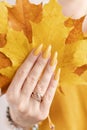 Female hand with a bottle of bright autumn yellow nail polish